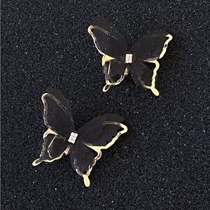 A pair of black golden butterfly clip-on earrings